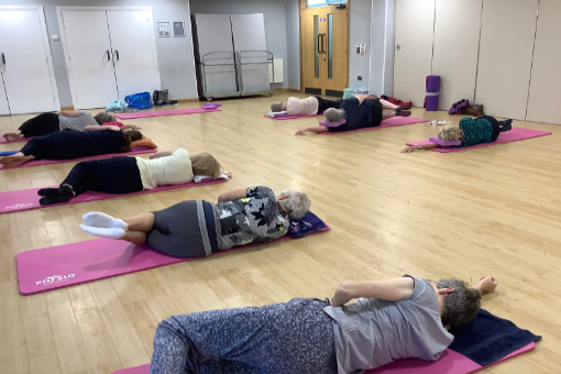 Group doing Pilates on floor mats in an exercise room